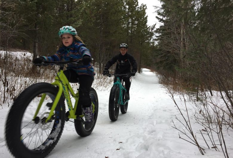 Girl and man riding fat bikes in the snow