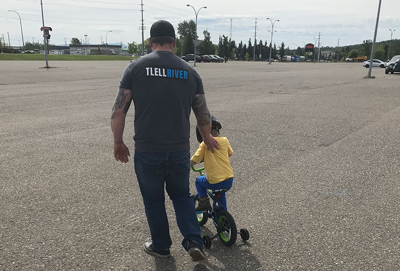 Dad teaching son how to ride a bike.