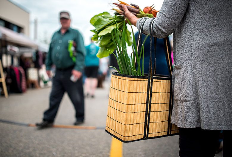 Woman holding bag of vegetables at Farmers' Market.