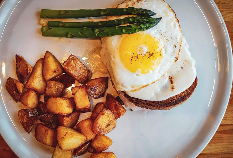 Egg on toast with hashbrowns and asparagus.