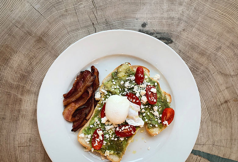 Avocado and poached egg on toast with bacon.