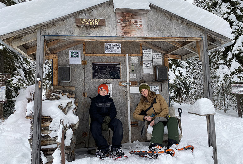 Woman and her son in front of snow covered cabin